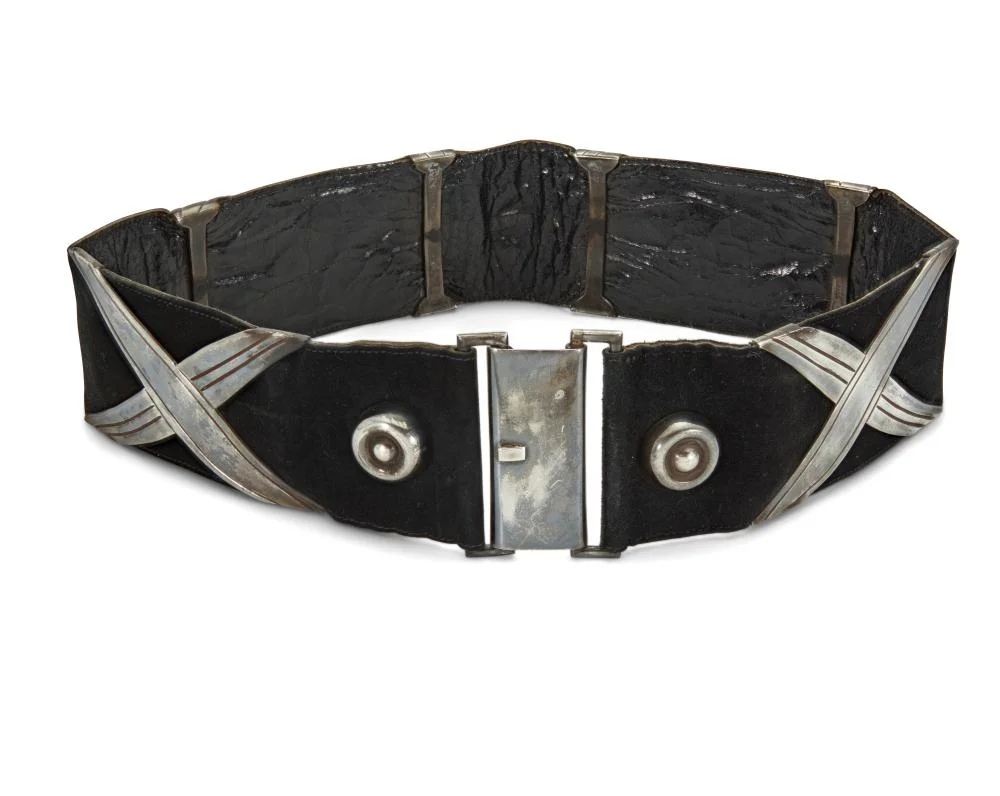 A Hector Aguilar 'Georgia O'Keefe' concho belt, c. 1940–1945. Four X-form silver conchos on black suede with a silver hook buckle. Buckle and one concho are stamped HA / Taxco / 990.
